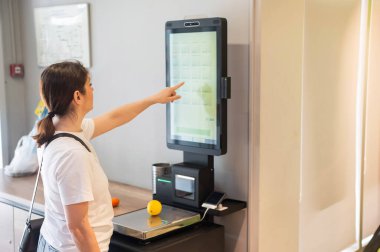 Kendini kontrol eden bir kadın limon tartıyor.