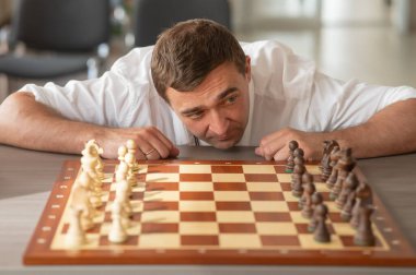 Orta yaşlı beyaz adam satranç oynuyor.