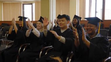 Mezunlar bir bankta oturur, konuşmaları dinler ve alkışlarlar.