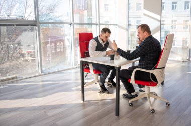 Masada otururken akıllı telefon kullanan iki beyaz adam.