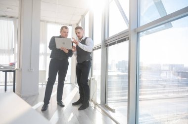 İki beyaz adam dizüstü bilgisayara bakıyor ve iş tartışıyorlar.