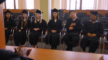 Çok uluslu öğrenciler sınıf arkadaşlarının konuşmasını dinlerler.