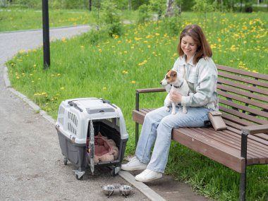 Sahibi Jack Russell Terrier ile birlikte güvenli bir yolculuk için bankta oturuyor.