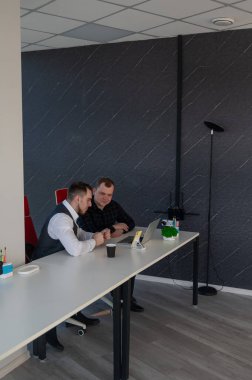 İki beyaz adam bir masada oturup iş tartışıyorlar.