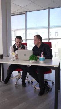 İki beyaz adam bir masada oturup iş tartışıyorlar.