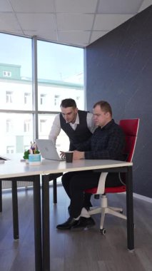 Beyaz adam çalışma masasında durmuş iş hakkında konuşuyor.