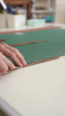 Kadın bir bronzlaştırıcı deri parçaları keser. Deri işçileri atölyesi