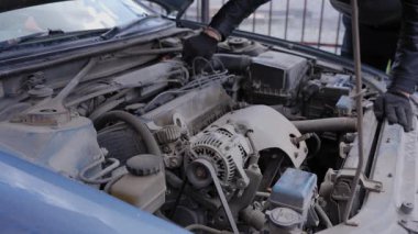 Beyaz adam bujileri değiştiriyor ve yüksek voltajlı kabloları söküyor.