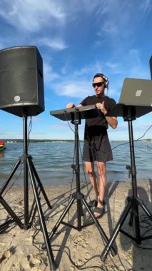Beyaz adam plajda DJ olarak çalışıyor.