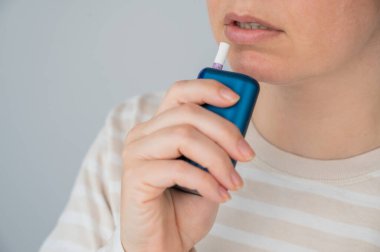 Elektronik sigara içen beyaz bir kadın. Tütün ısıtma sistemi