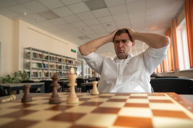 Orta yaşlı beyaz adam satranç oynuyor.