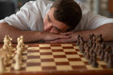 Orta yaşlı beyaz adam satranç oynuyor.