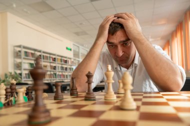 Orta yaşlı beyaz adam satranç oynuyor.