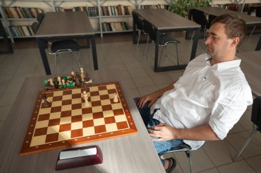 Orta yaşlı beyaz adam satranç oynuyor.