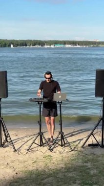 Beyaz adam plajda DJ olarak çalışıyor.