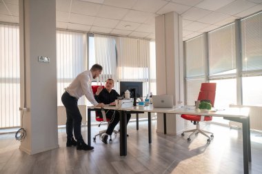 Beyaz adam çalışma masasında durmuş iş hakkında konuşuyor.