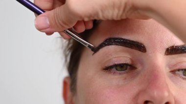 Beyaz kadın kaş boyama prosedürü uyguluyor.