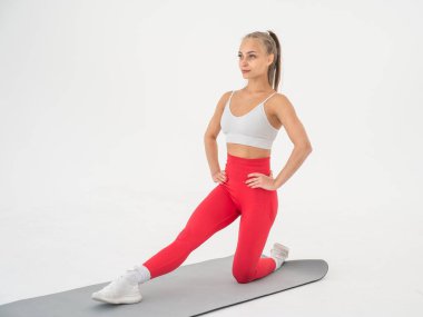 Beyaz arka plan üzerinde bölme egzersizleri yapan genç kadın