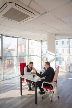 Masada otururken akıllı telefon kullanan iki beyaz adam.