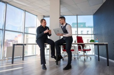 Ofiste iş tartışan iki beyaz adam. İşitme cihazı olan bir iş adamı.