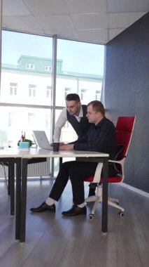 Beyaz adam çalışma masasında durmuş iş hakkında konuşuyor.