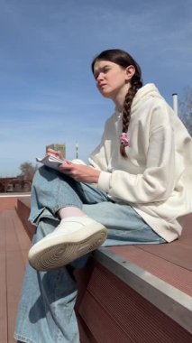 Açık havada kalemle çizim yapan beyaz bir kadın.