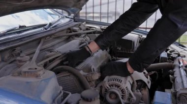 Beyaz adam bujileri değiştiriyor ve yüksek voltajlı kabloları söküyor.