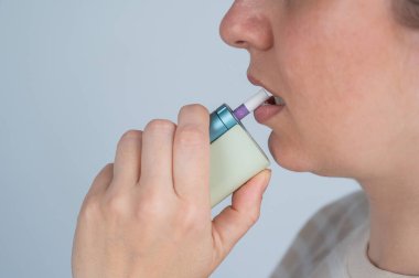 Elektronik sigara içen beyaz bir kadın. Tütün ısıtma sistemi