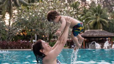 Beyaz kadın tatilde havuzda yüzerken oğlunu kucağına aldı