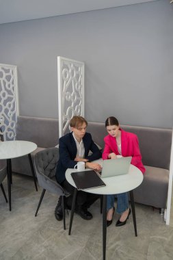 Meslektaşlar dizüstü bilgisayarda oturup iş konuşuyorlar.