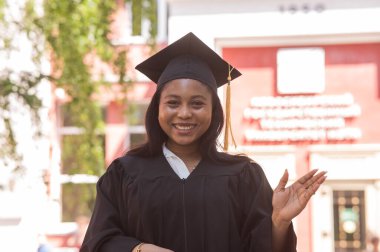 Mezuniyet elbisesi içinde mutlu bir Afrikalı kadın.
