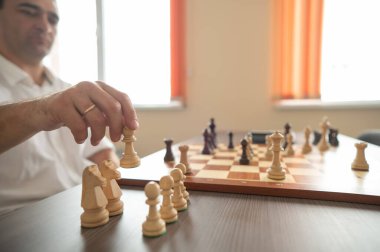 Orta yaşlı beyaz adam satranç oynuyor.