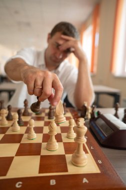 Orta yaşlı beyaz adam satranç oynuyor.