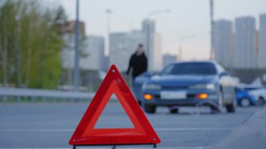 Uyarı üçgeni. Adam halatı arabadan ayırıyor.