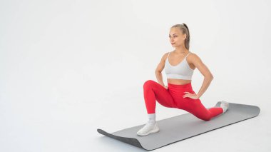 Beyaz arka plan üzerinde bölme egzersizleri yapan genç kadın