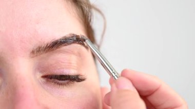Beyaz kadın kaş boyama prosedürü uyguluyor.