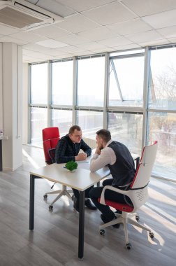 İki beyaz adam bir iş toplantısında iletişim kuruyor.