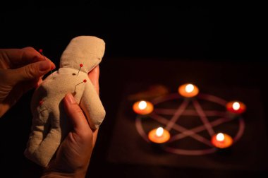 Kadın vudu bebeğine iğne batırıyor.