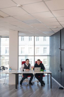 İki beyaz adam bir masada oturup iş tartışıyorlar.