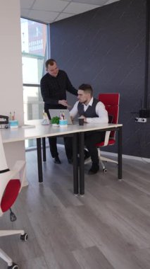 Beyaz adam çalışma masasında durmuş iş hakkında konuşuyor.