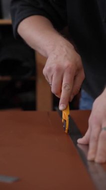 Deri işçisi atölyede deri kesip ölçüyor.