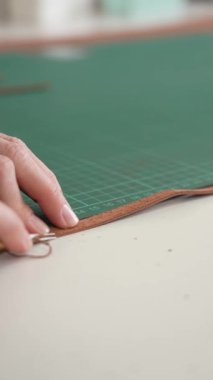 Kadın bir bronzlaştırıcı deri parçaları keser. Deri işçileri atölyesi