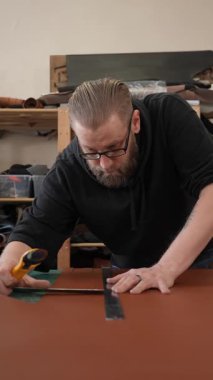 Beyaz sakallı adam bir atölyede bronzlaştırıcı olarak çalışıyor.