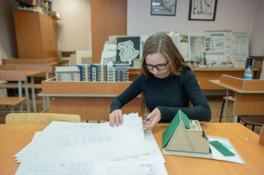 Kafkasyalı genç bir kadın bir binanın modelini yapıyor. İnşaat üniversitesi öğrencisi.