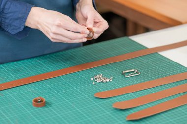 Bir kadın deri kemere aksesuar takar. Deri işçileri atölyesi