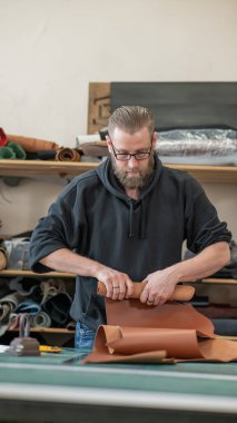 Beyaz sakallı adam bir atölyede bronzlaştırıcı olarak çalışıyor.