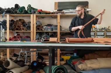 Beyaz sakallı adam bir atölyede bronzlaştırıcı olarak çalışıyor.