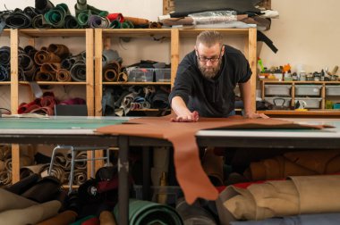 Beyaz sakallı adam bir atölyede bronzlaştırıcı olarak çalışıyor.