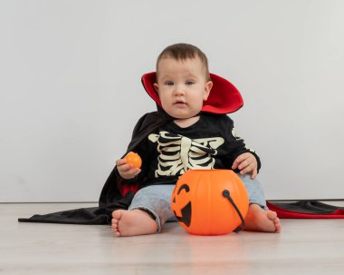 Beyaz arka planda şeker sepeti tutan Dracula Cadılar Bayramı kostümlü beyaz tatlı çocuk.