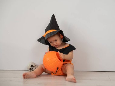 Cadılar bayramı balkabağı kostümlü beyaz arka planda şeker sepeti tutan yakışıklı beyaz çocuk.